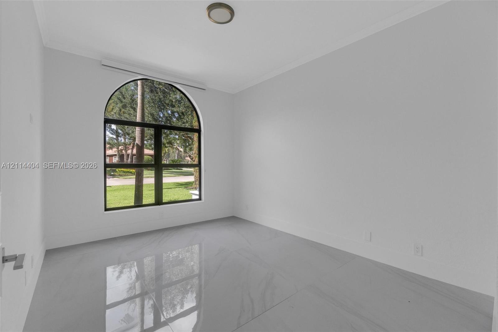 Large arched window, neutral wall palette, and polished large-format tile flooring