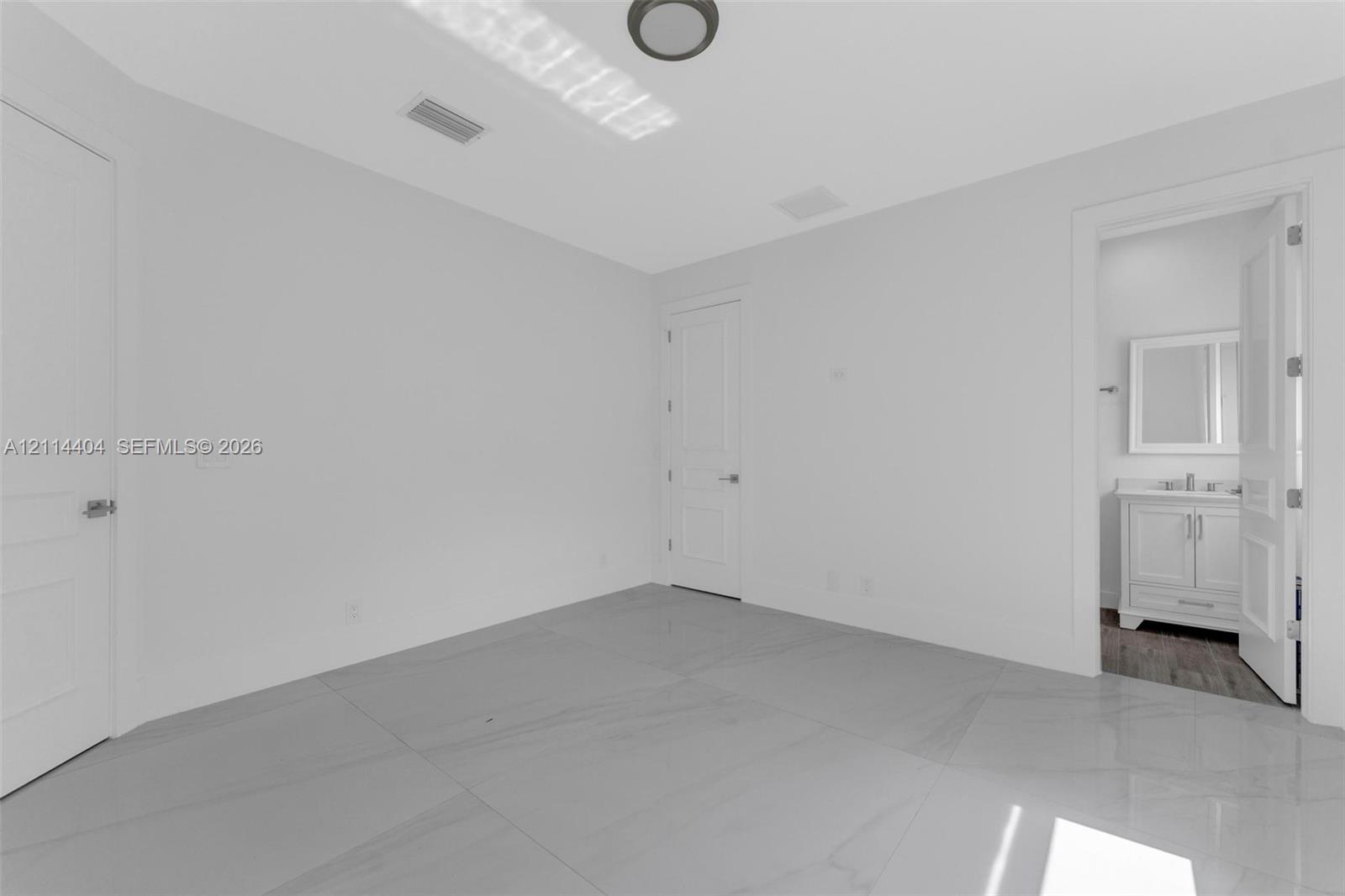 Room featuring large-format tile flooring, smooth ceilings with flush-mount lighting, and solid-core panel doors