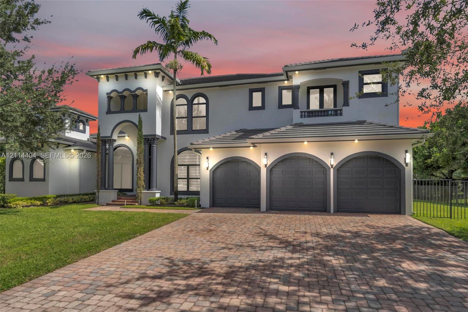 Two-story stucco exterior with arched detailing, concrete tile roof, paver driveway, and a three-car garage Two-story stucco exterior with arched detailing, concrete tile roof, paver driveway, and a three-car garage