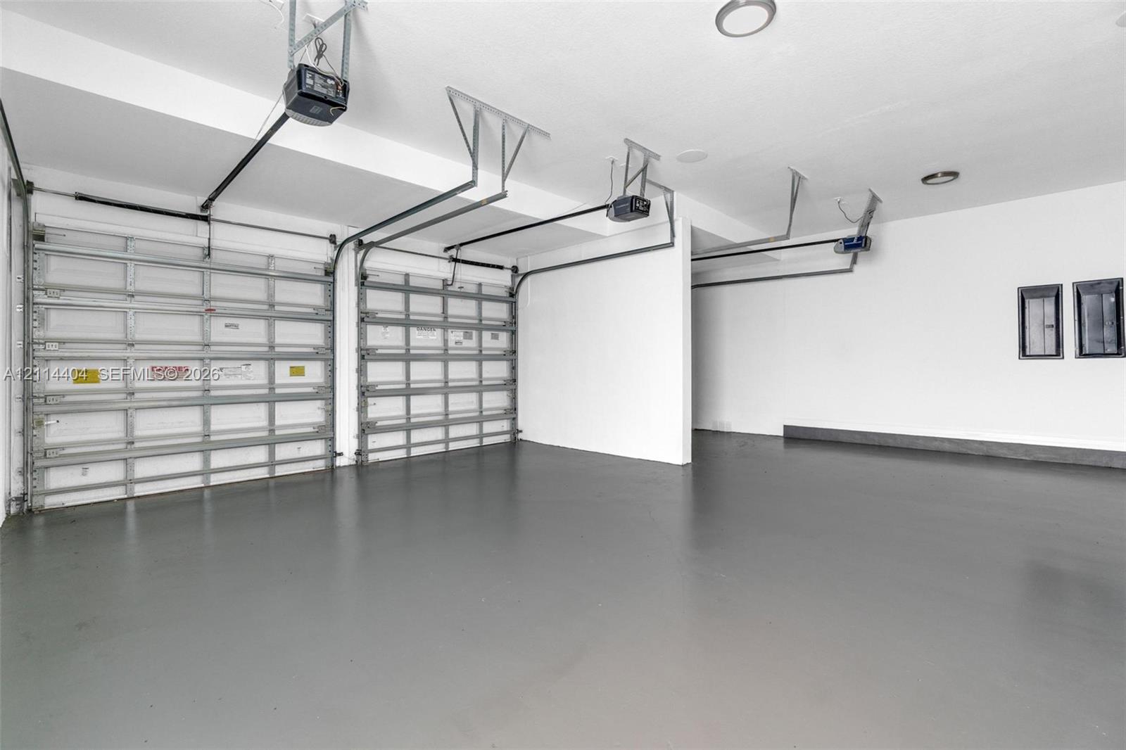 Multi-car garage featuring a smooth-finish floor, white walls, and automated overhead door openers