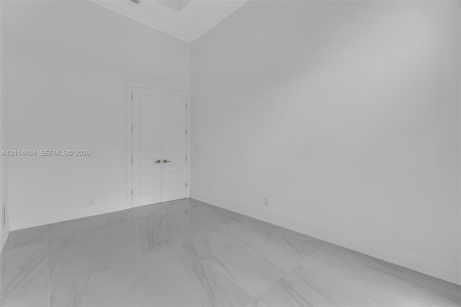 High-ceiling room featuring large-format tile flooring and double-panel doors