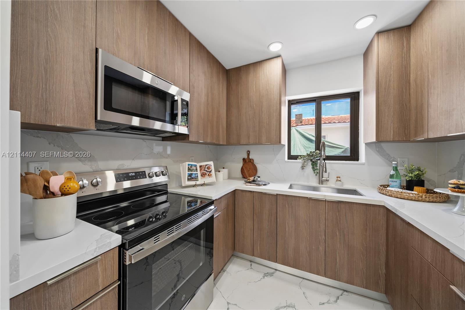 Kitchen featuring wood-finish cabinetry, stainless steel appliances, stone-patterned countertops, a full-height stone-patterned backsplash, and stone-patterned flooring Kitchen featuring wood-finish cabinetry, stainless steel appliances, stone-patterned countertops, a full-height stone-patterned backsplash, and stone-patterned flooring