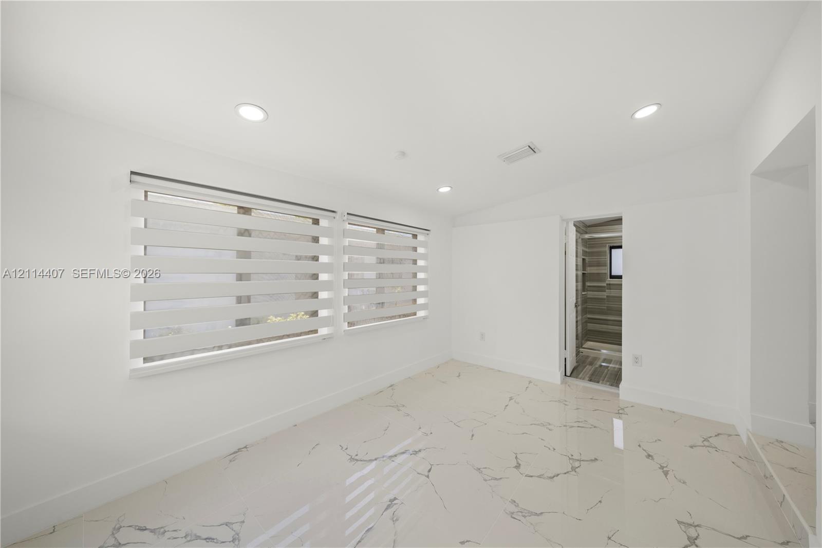 Polished stone flooring with veining, recessed lighting, and dual windows featuring horizontal banded shades