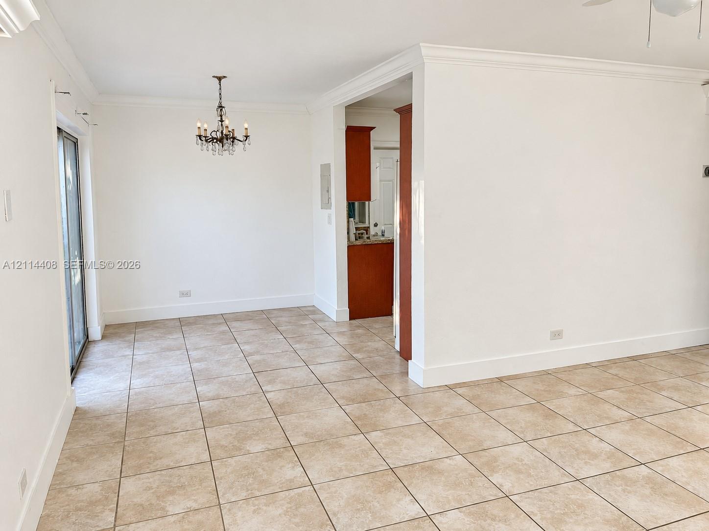 Ceramic tile flooring, crown molding, multi-arm chandelier, and sliding glass door