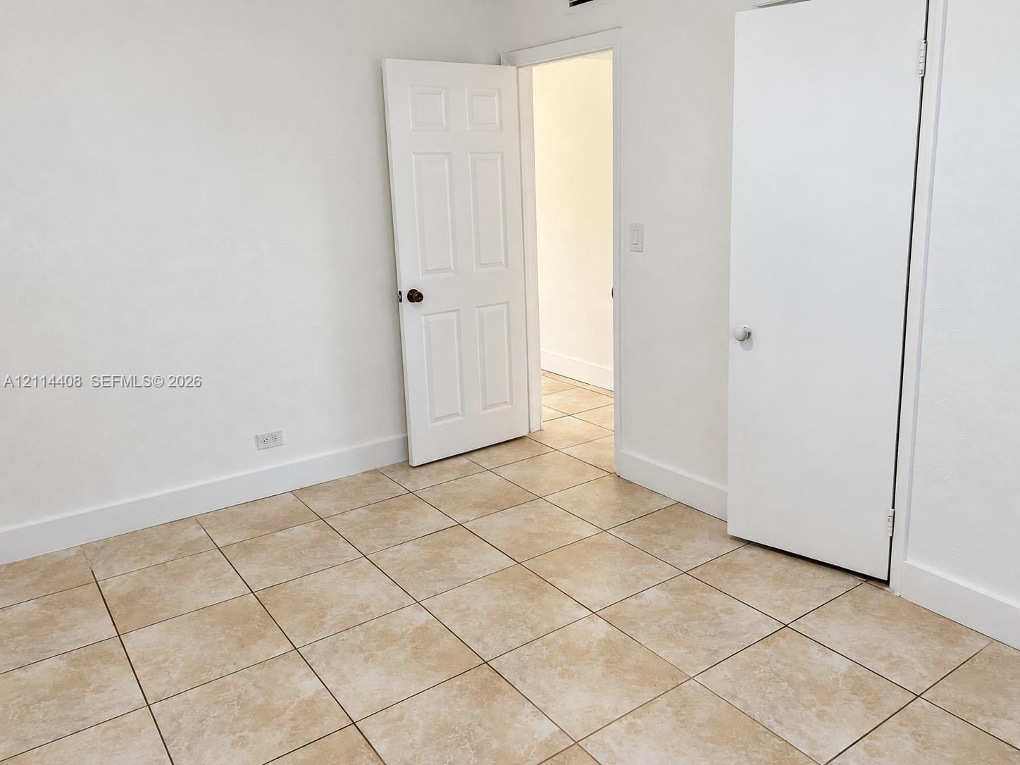 Interior space featuring neutral tile flooring, six-panel interior doors, and a built-in closet with a swing-style door
