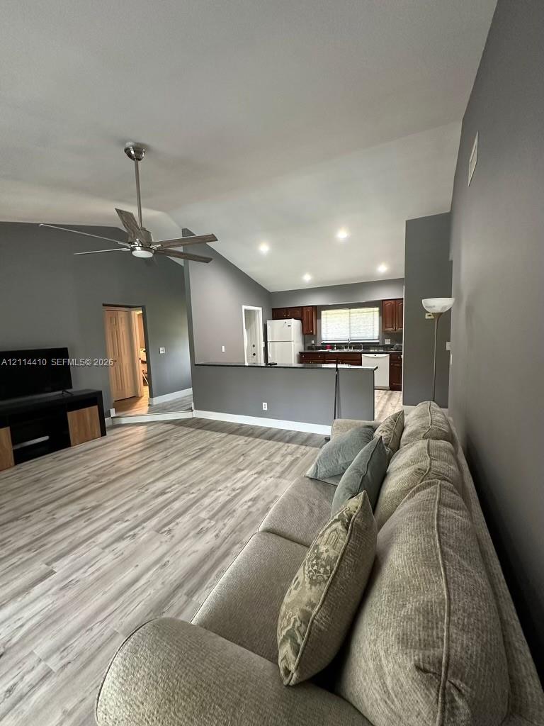 Vaulted ceilings, wood-finish flooring, recessed lighting, ceiling fan, and peninsula kitchen layout