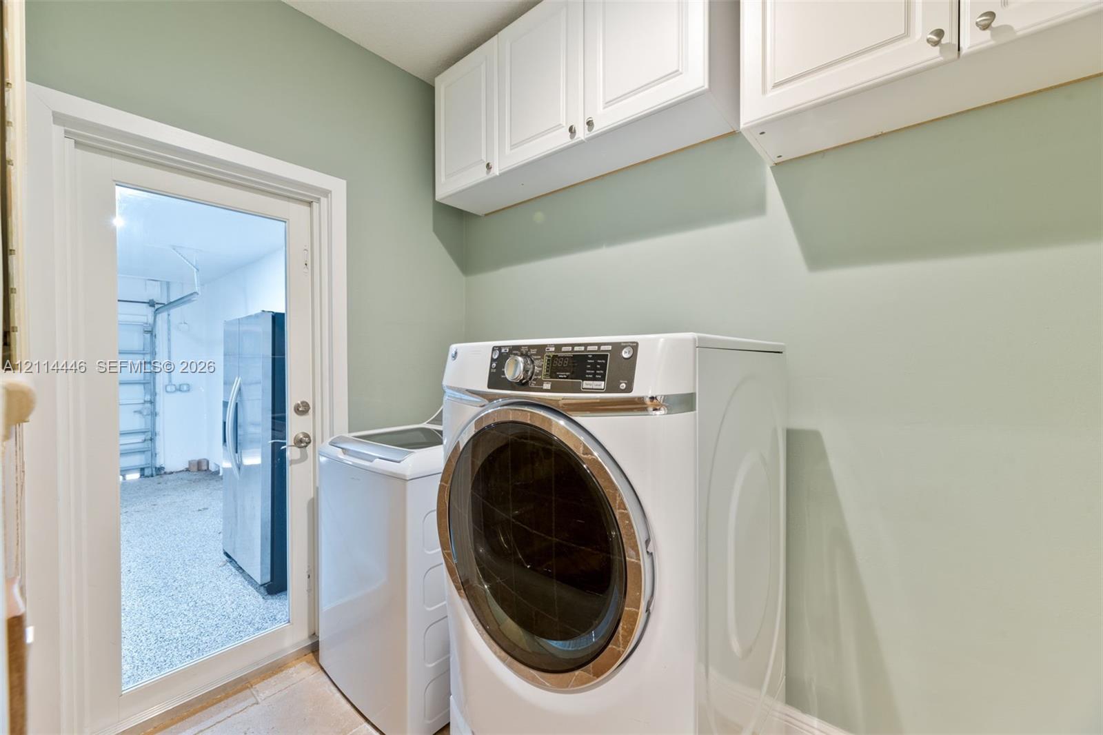 Utility area featuring white shaker-style wall cabinets and a glass-panel door