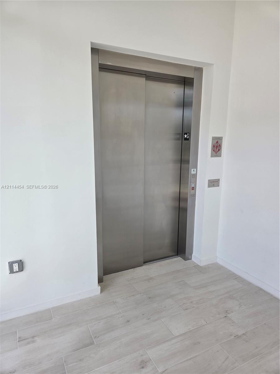 Stainless steel elevator featuring a brushed metal finish and neutral wood-finish flooring