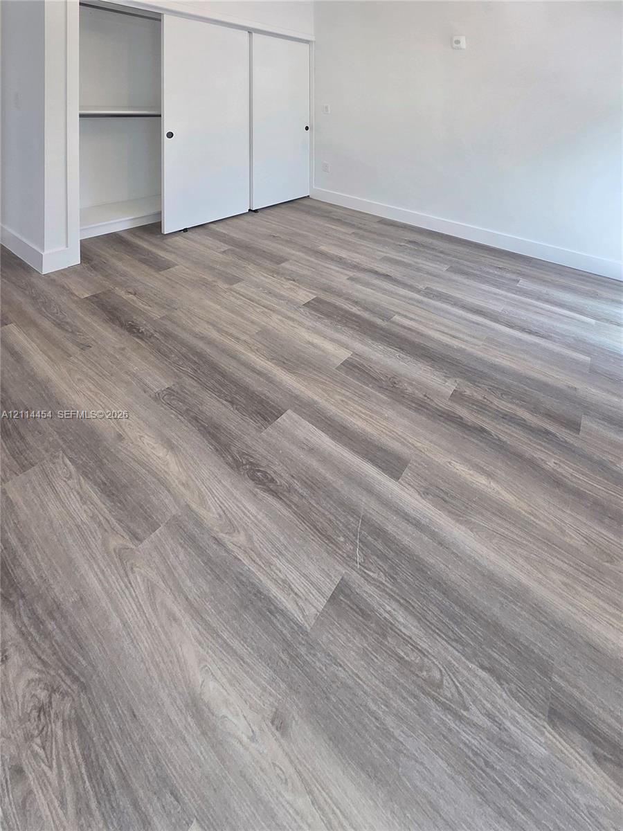 Wood-finish flooring, neutral wall tones, and a built-in closet with sliding doors
