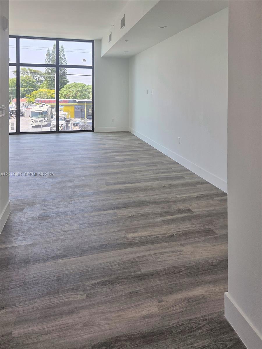 Open-concept space featuring floor-to-ceiling windows with black metal framing and wood-finish flooring