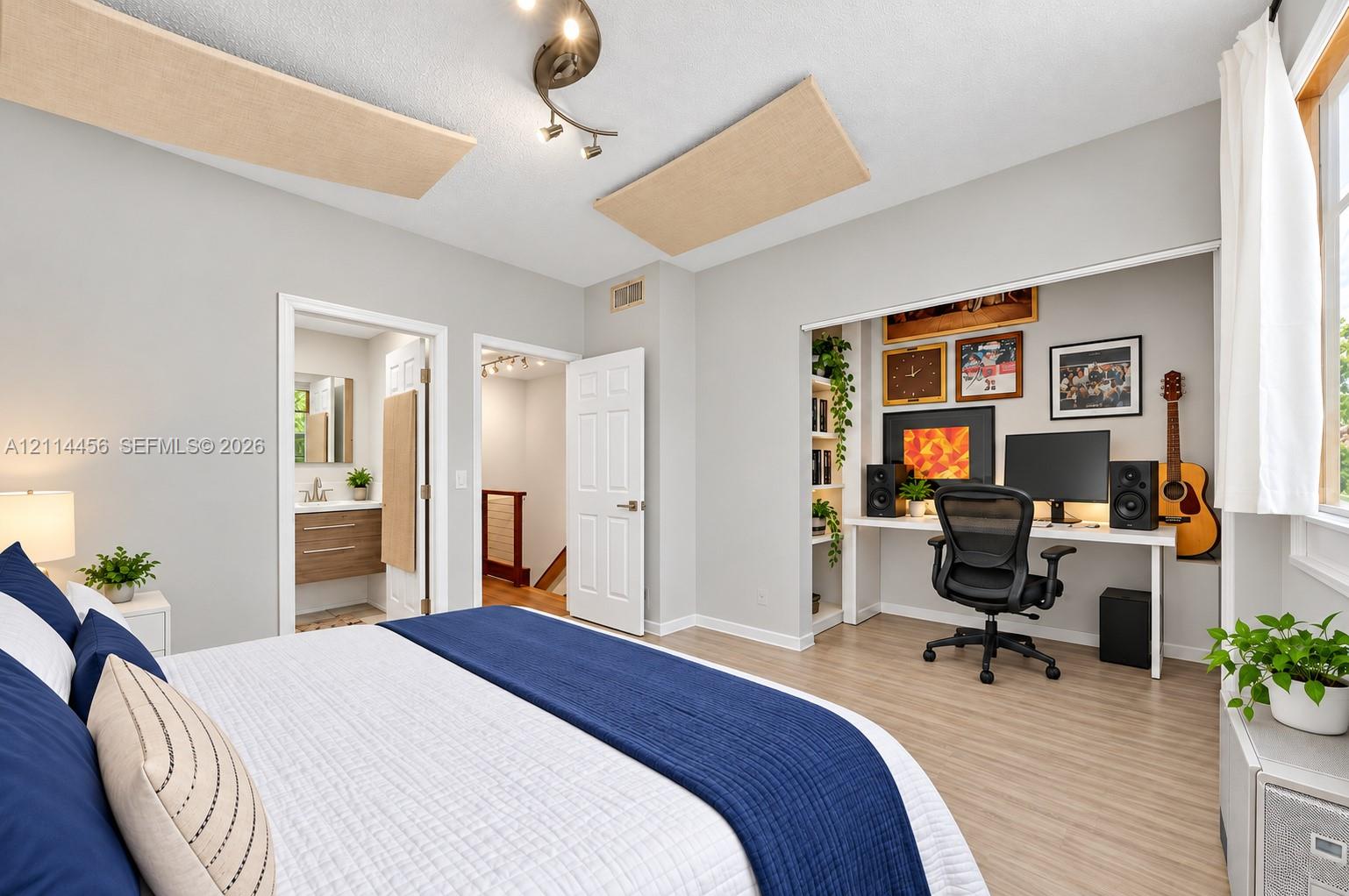 Room featuring wood-finish flooring, recessed built-in shelving, a dedicated work alcove, and a multi-directional ceiling light fixture