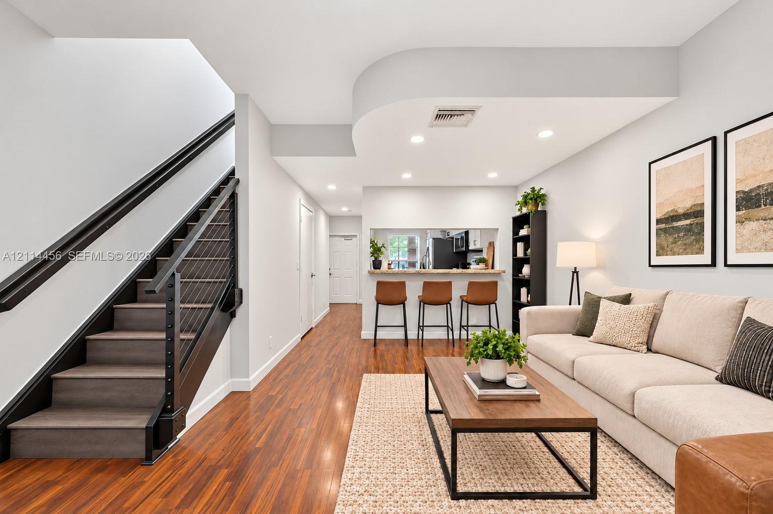Interior space featuring wood-finish flooring, recessed lighting, and a staircase with matte black railings and cable balusters