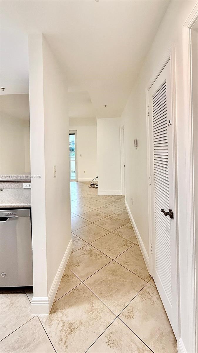 Diagonal tile flooring, stainless steel dishwasher, and louvered closet door with a metallic knob