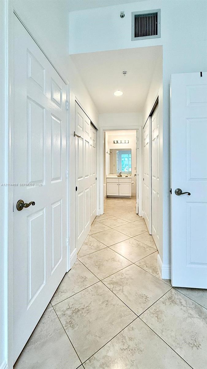 Hallway featuring diagonal-set tile flooring, multiple six-panel interior doors, and recessed lighting