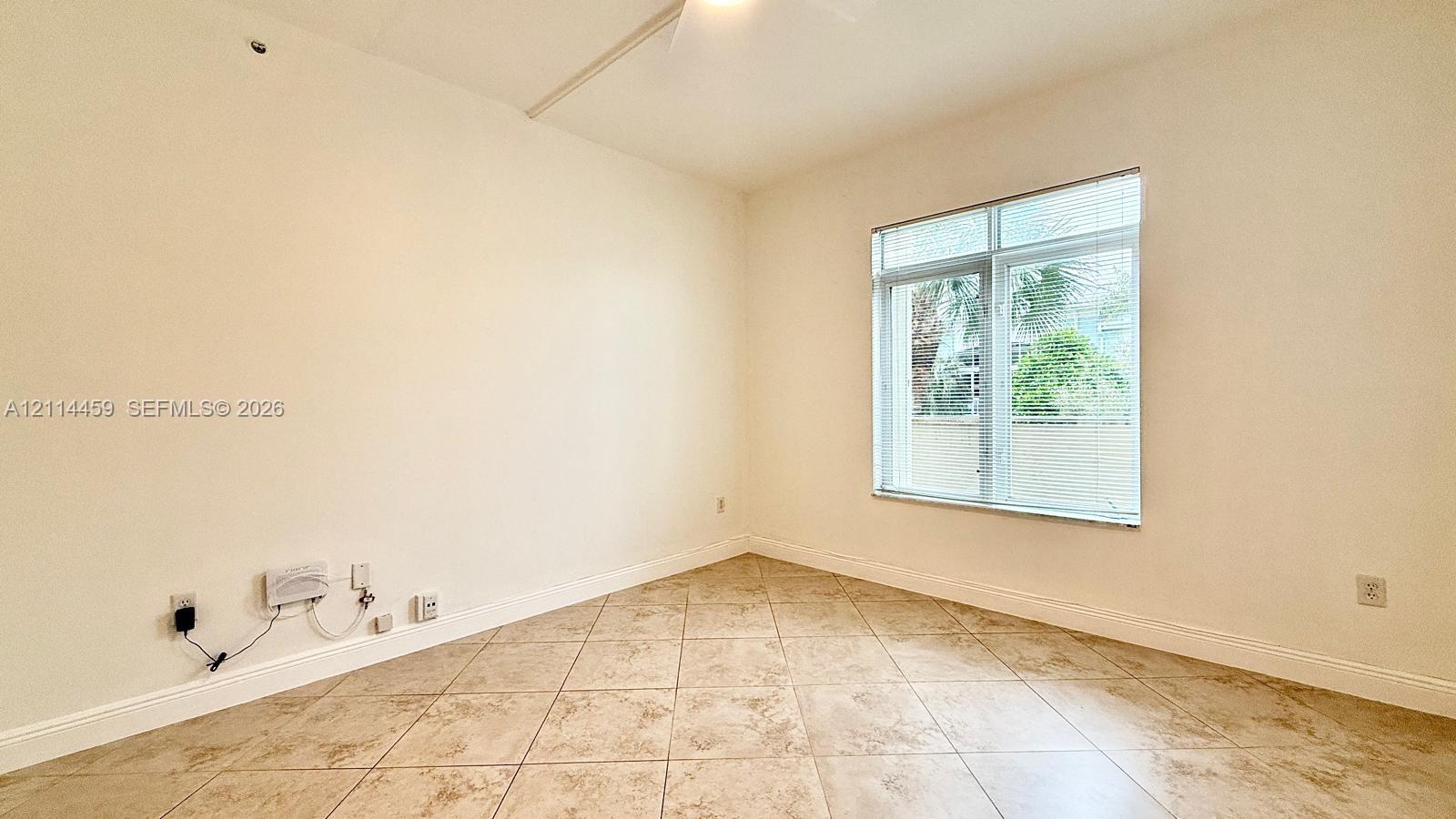 Interior room featuring neutral wall paint, tile flooring, and a window with a transom light