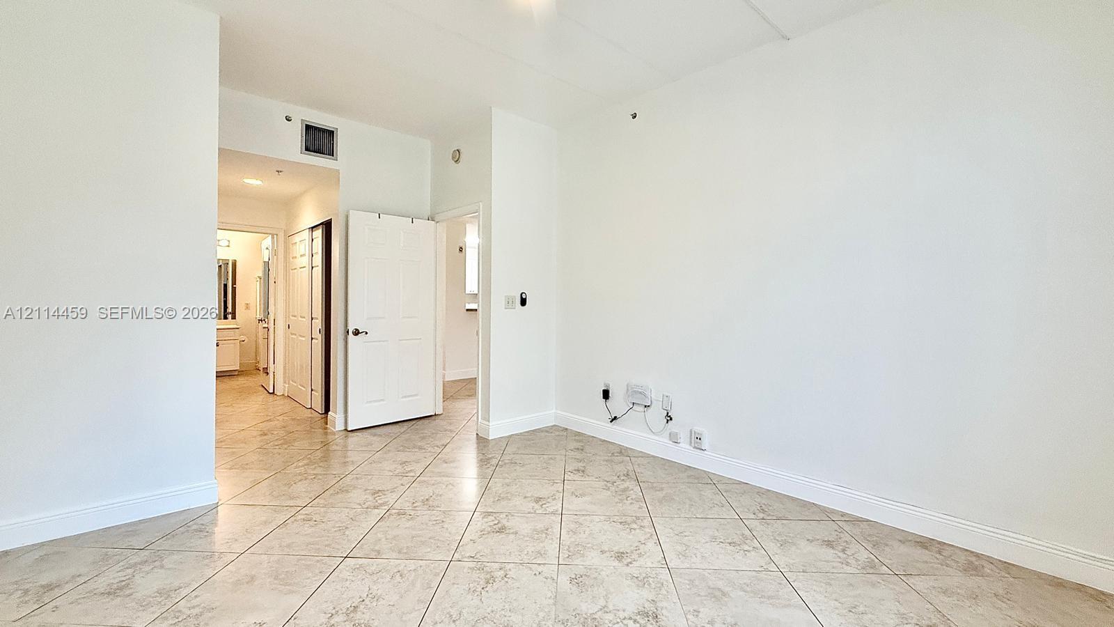 Neutral-toned tile flooring set in a diagonal pattern, white six-panel interior doors, and recessed ceiling lighting