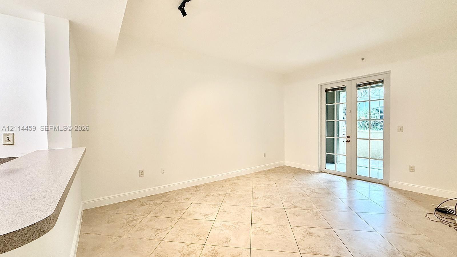Neutral-toned ceramic tile flooring, French doors with glass panes, and a built-in kitchen breakfast bar