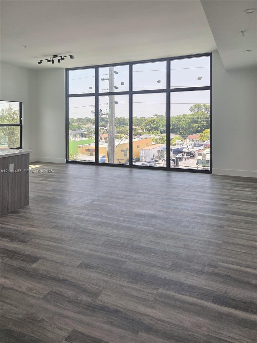 Floor-to-ceiling windows with black frames, wood-finish flooring, recessed lighting, and multi-directional track lighting