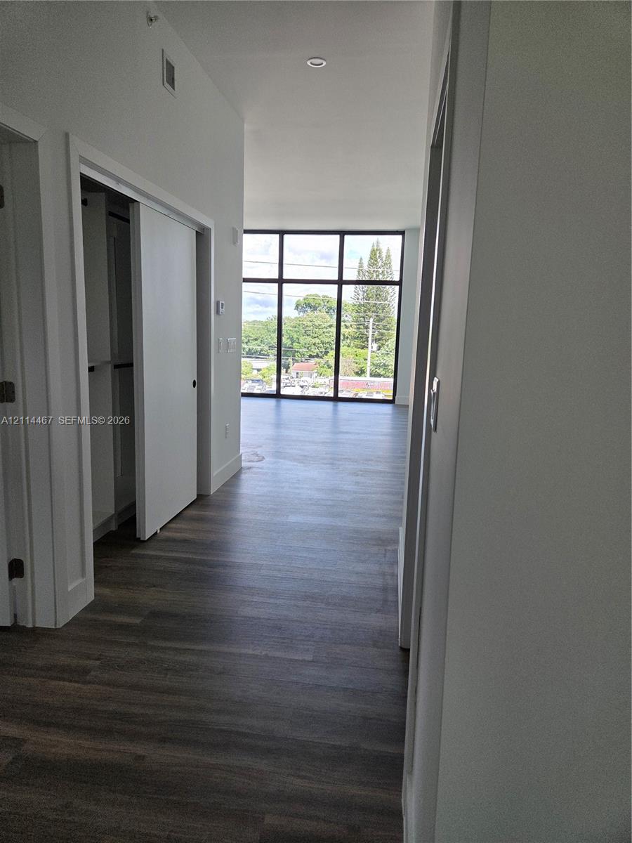 Wood-finish flooring, floor-to-ceiling windows with a black frame, sliding closet doors, and recessed lighting