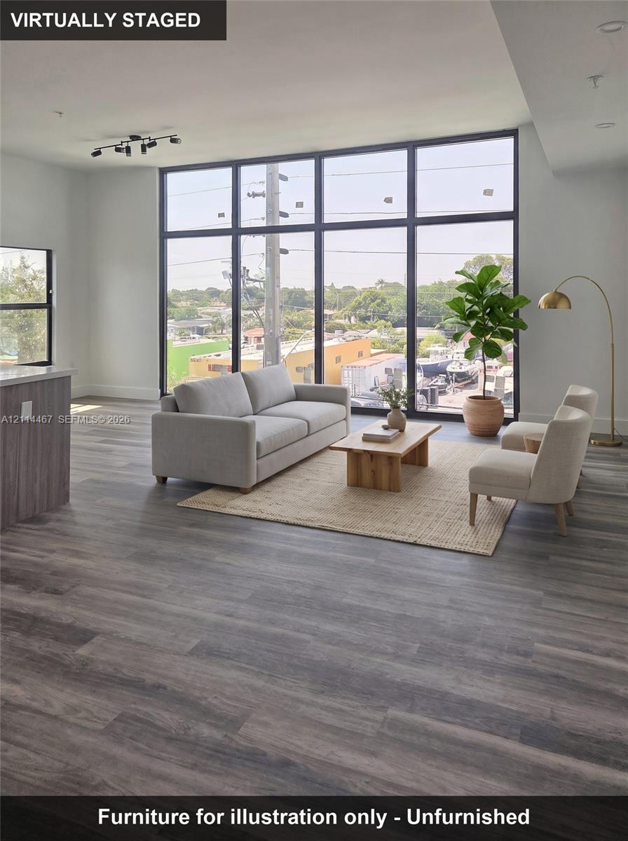 Floor-to-ceiling windows with black frames, wood-finish flooring, and multi-directional track lighting