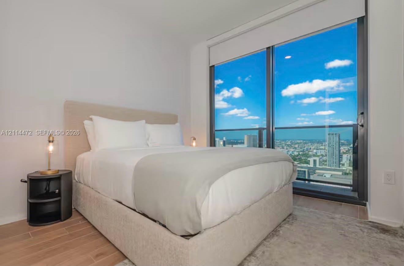 Floor-to-ceiling glass sliding door, metal-frame balcony railing, wood-finish flooring, and recessed ceiling lighting