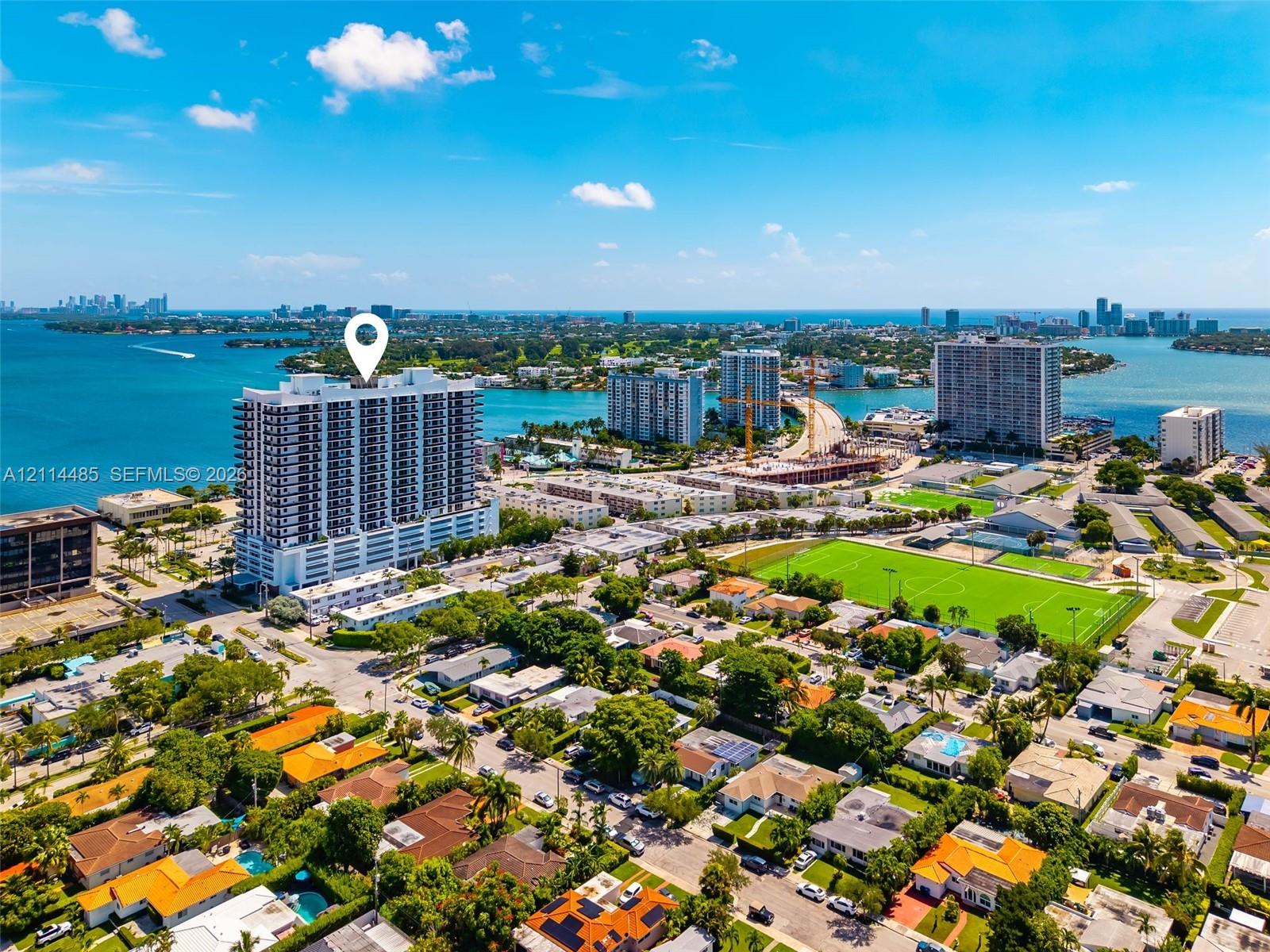 High-rise residential building situated on a waterfront peninsula, featuring balconies and proximity to the bay