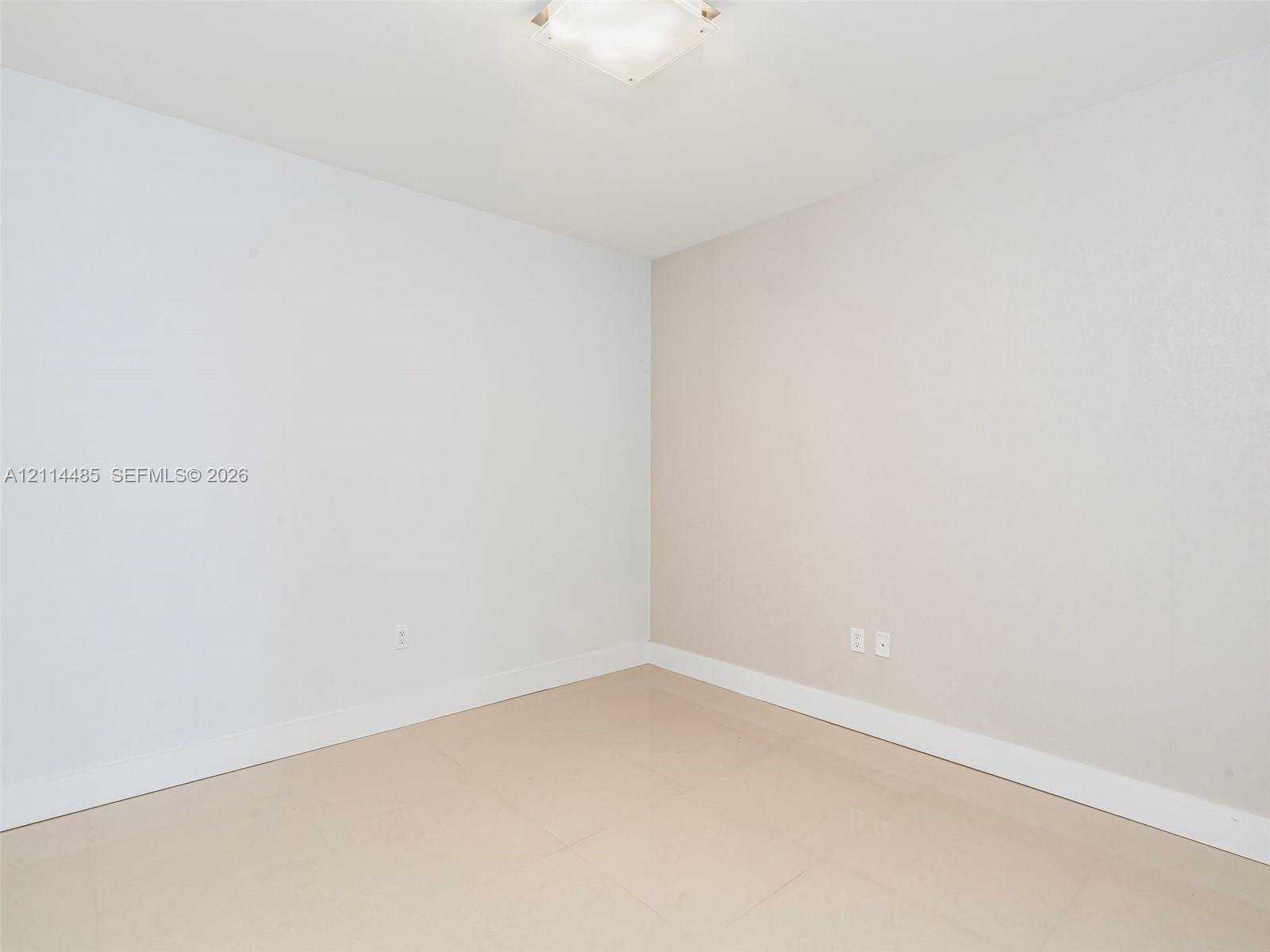 Neutral interior space featuring polished tile flooring, light-toned walls, and a square ceiling-mounted light fixture