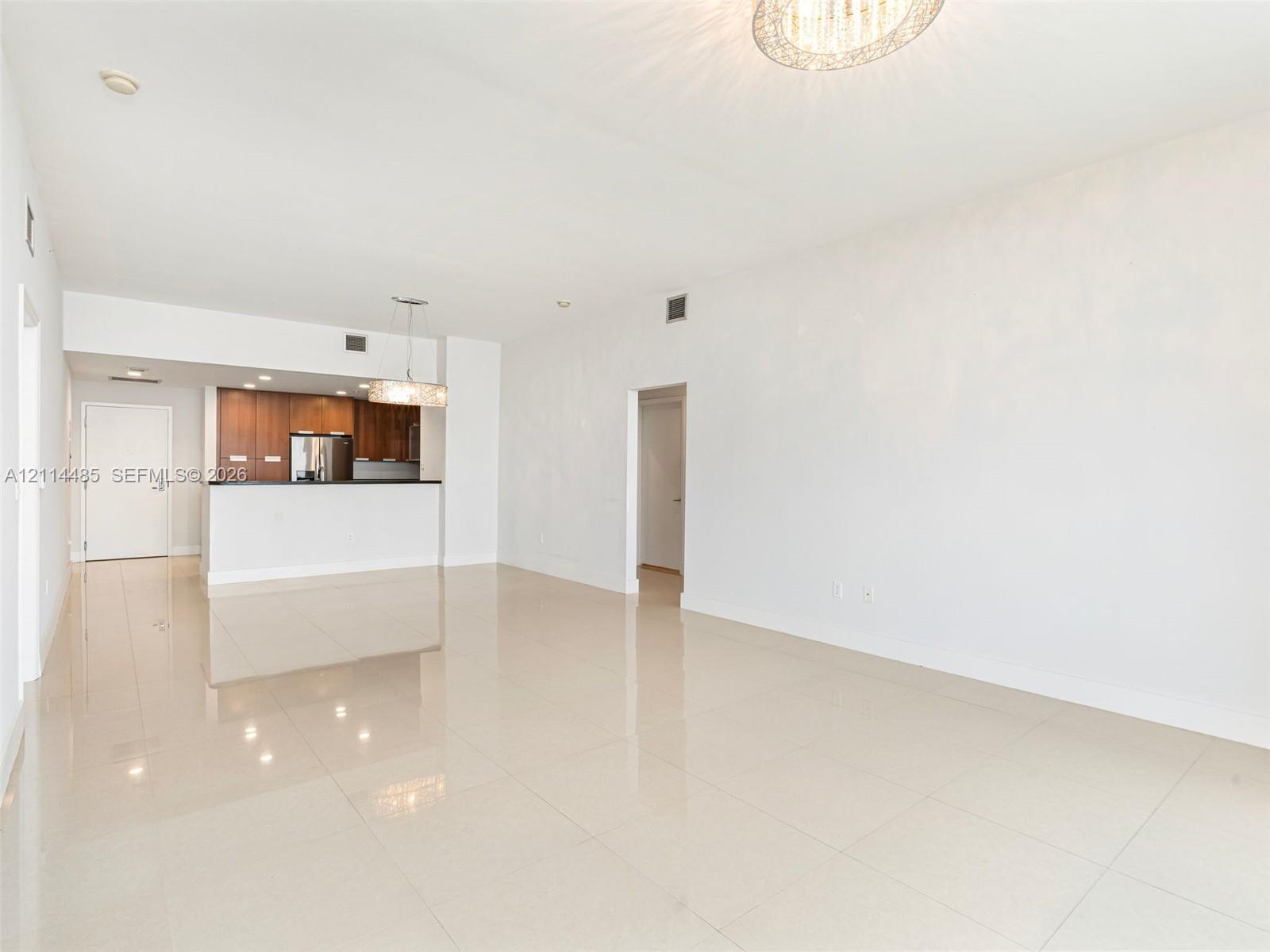 Large-format tile flooring, kitchen featuring wood cabinetry and stone countertops, and recessed pendant lighting