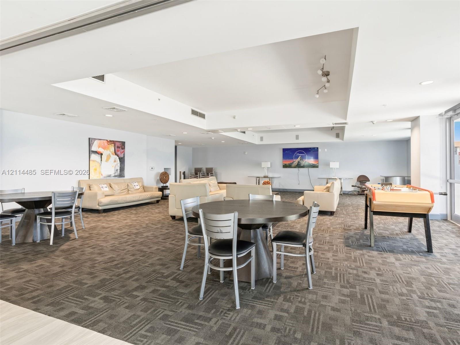 Open-concept common area featuring recessed ceiling details, neutral carpeting, and track lighting
