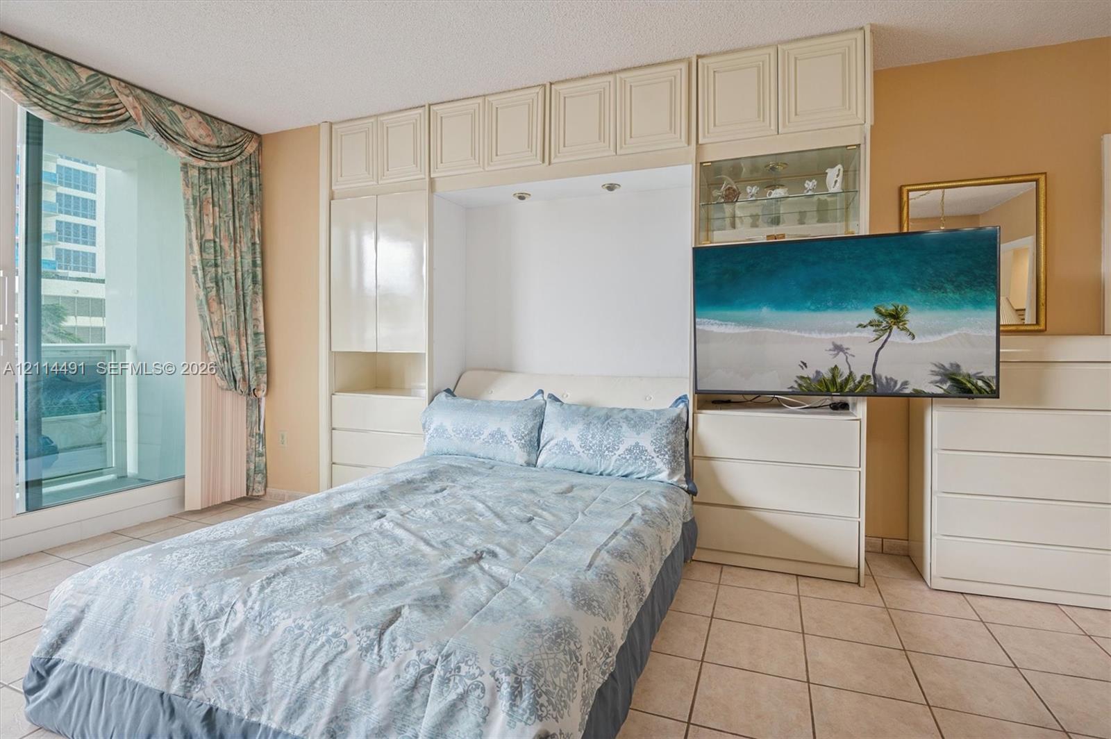 Built-in floor-to-ceiling cabinetry, recessed lighting, tile flooring, and sliding glass door with balcony access