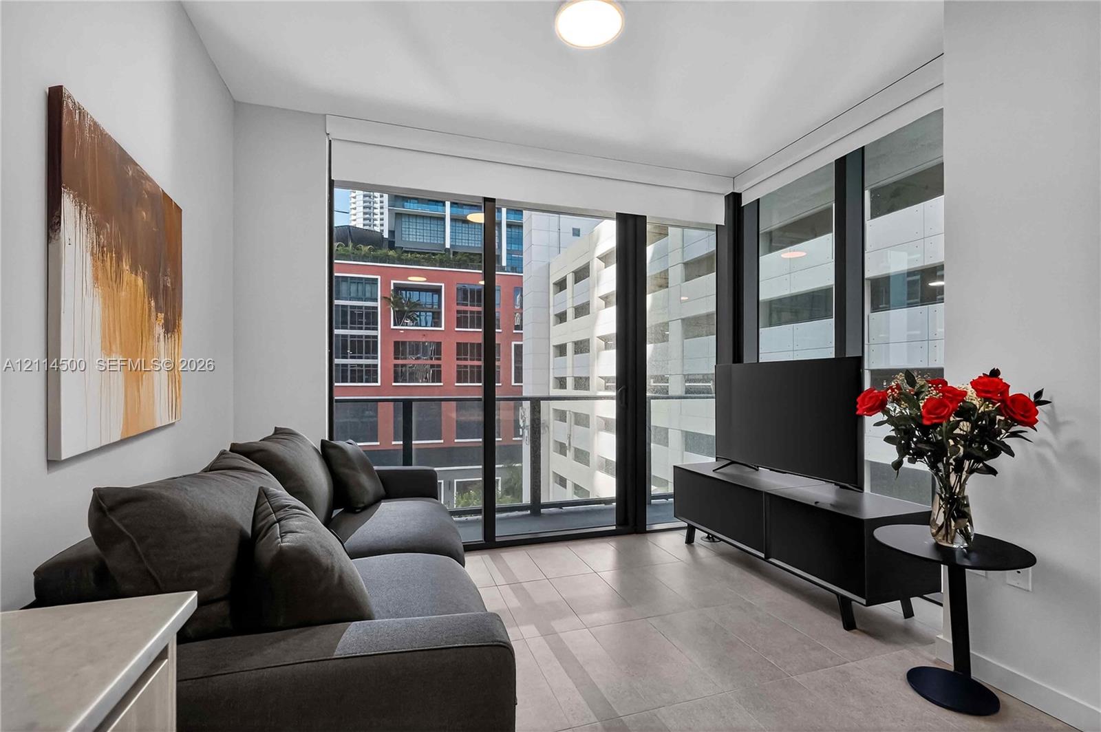 Floor-to-ceiling windows, private balcony, neutral large-format tile flooring, and crisp white wall finishes Floor-to-ceiling windows, private balcony, neutral large-format tile flooring, and crisp white wall finishes