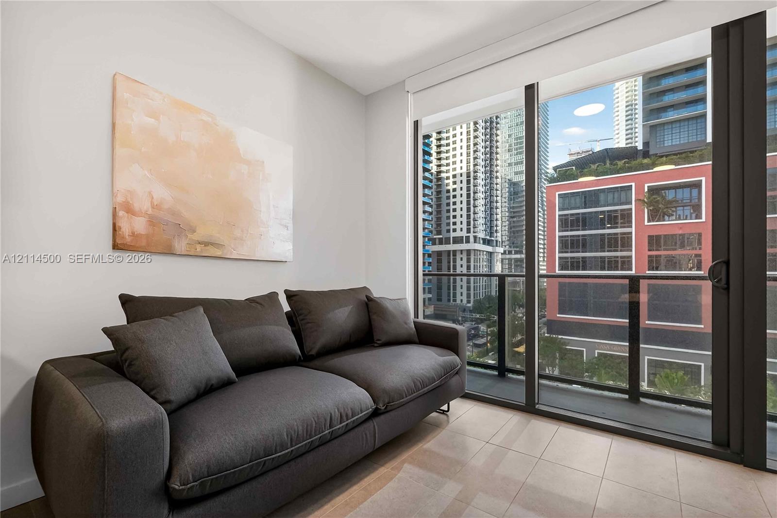 Floor-to-ceiling glass sliding door, neutral tile flooring, and integrated black metal balcony railing