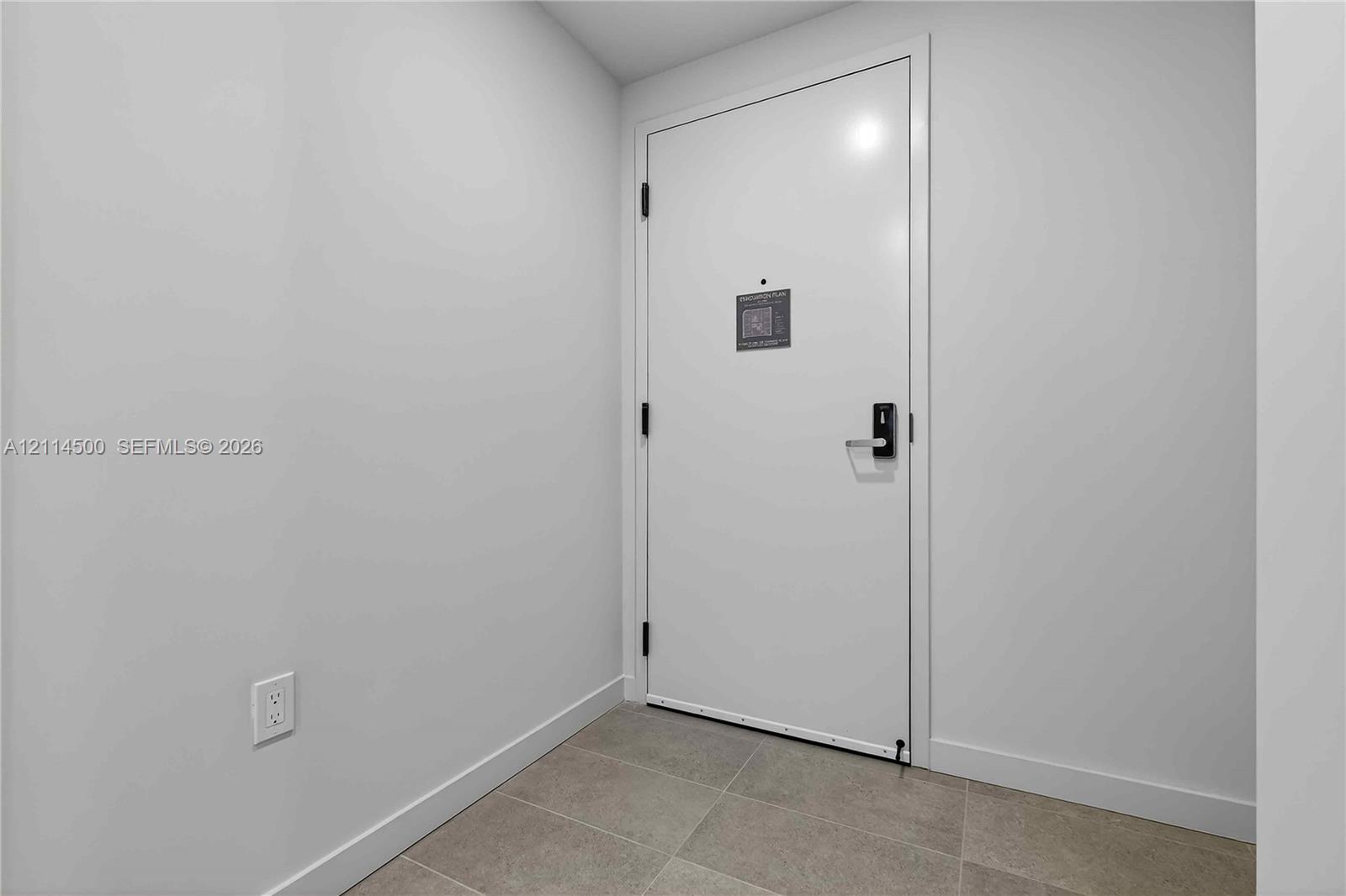 Interior entrance featuring a solid-core white door, matte black hardware, and neutral-toned floor tile