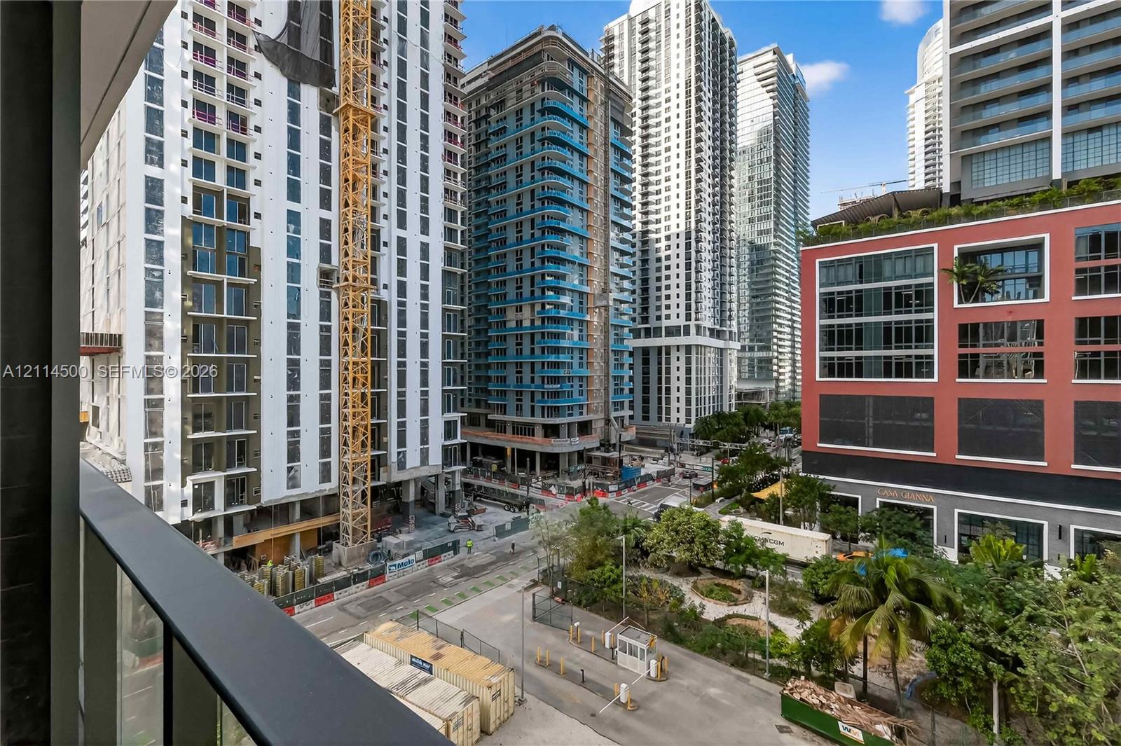 Balcony featuring a matte black metal railing overlooking an urban streetscape with high-rise structures and landscaped grounds