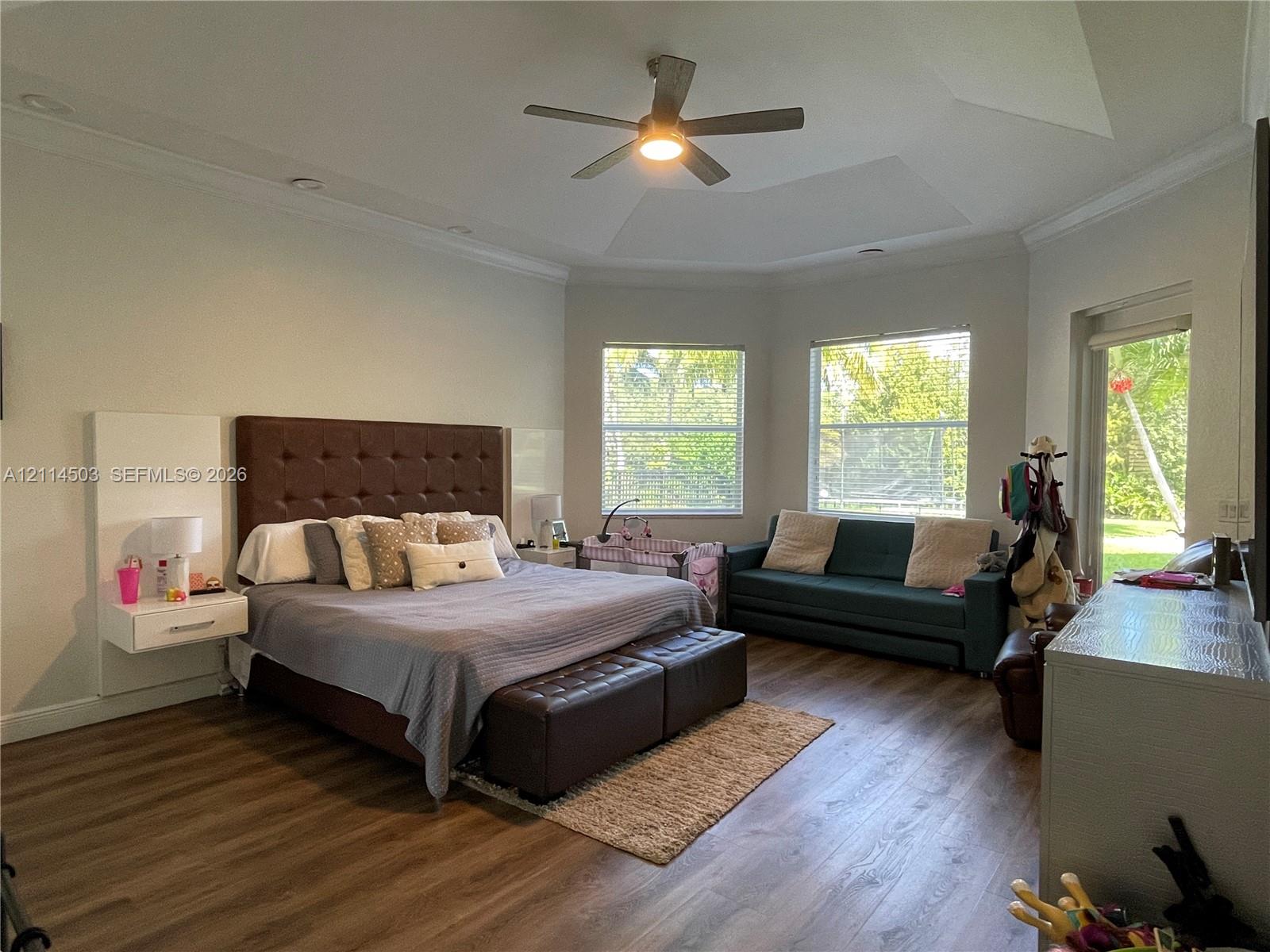 Tray ceiling with recessed lighting, wood-finish flooring, and built-in floating bedside tables