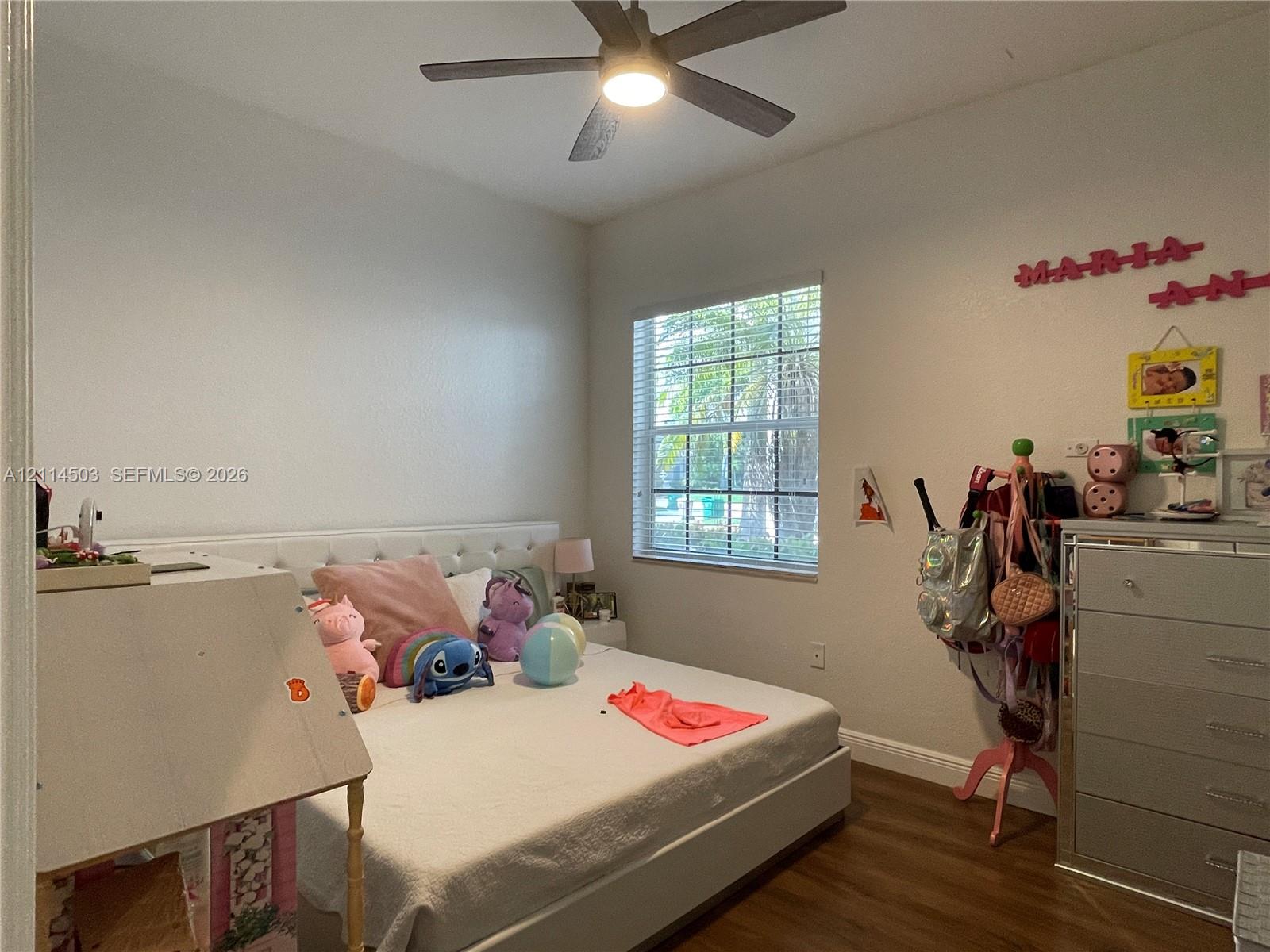 Interior space featuring wood-finish flooring, a multi-blade ceiling fan with integrated lighting, and a single-hung window with a grid pattern