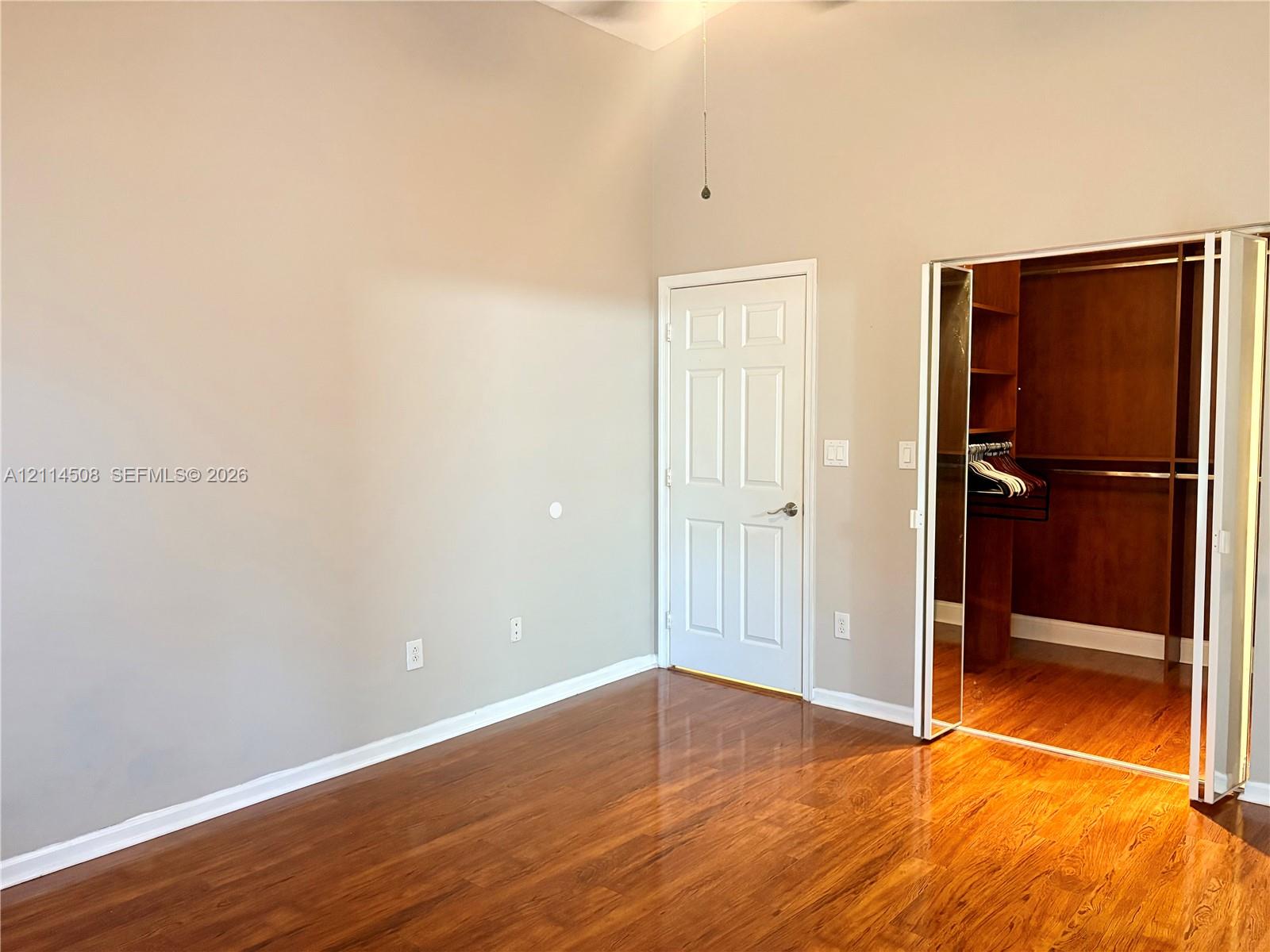Room featuring vaulted ceilings, wood-finish flooring, and a walk-in closet with built-in shelving