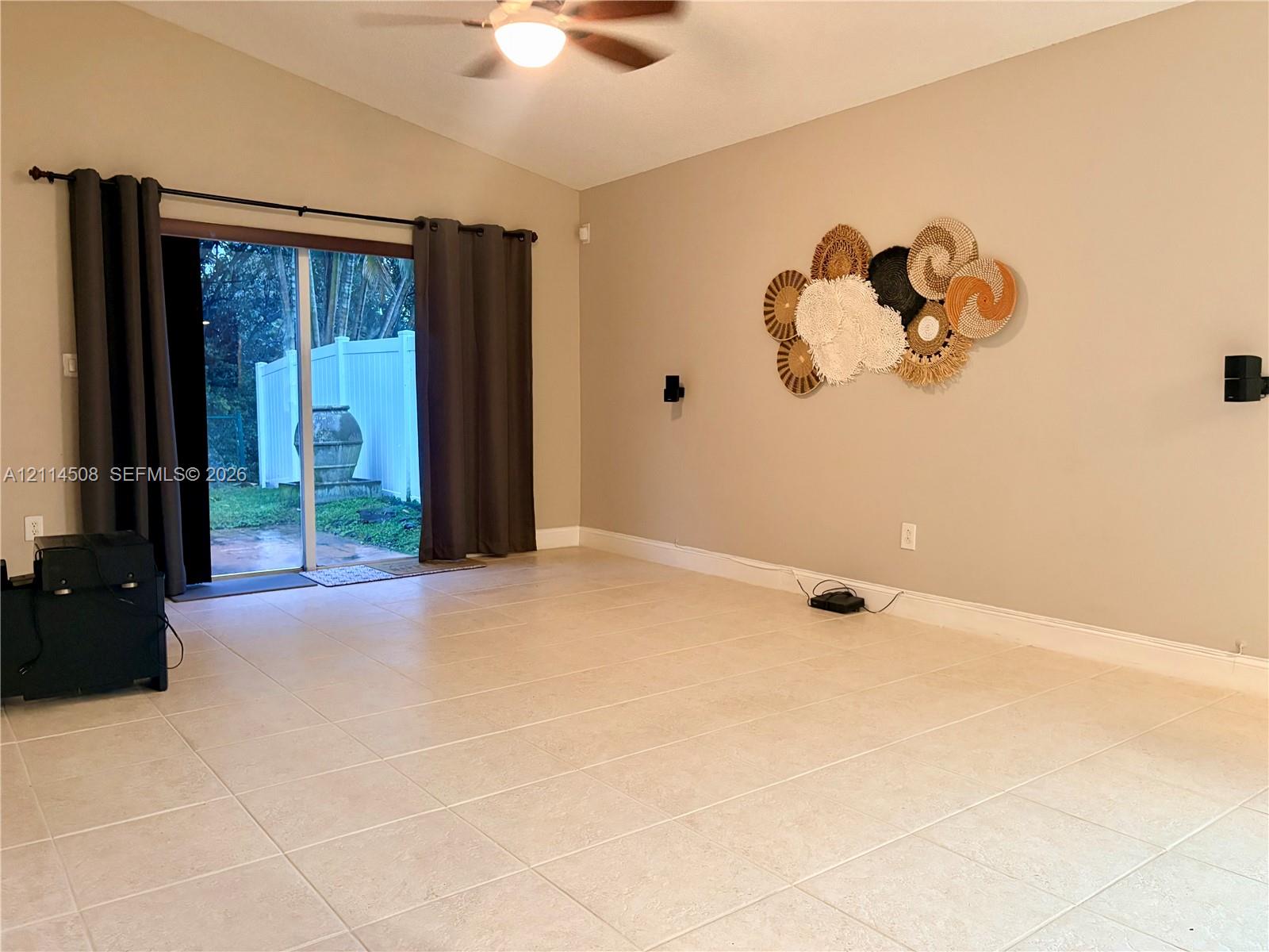 Vaulted ceiling, large ceramic floor tiling, and sliding glass doors providing outdoor access