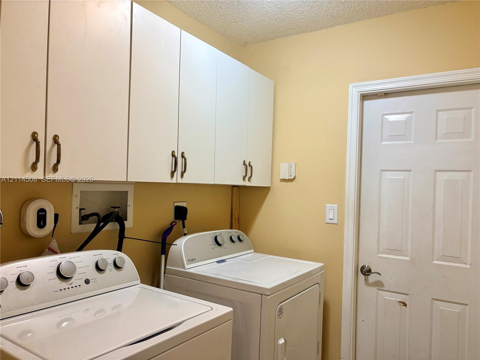Laundry area featuring white flat-panel upper cabinetry, a six-panel interior door, and recessed plumbing connections