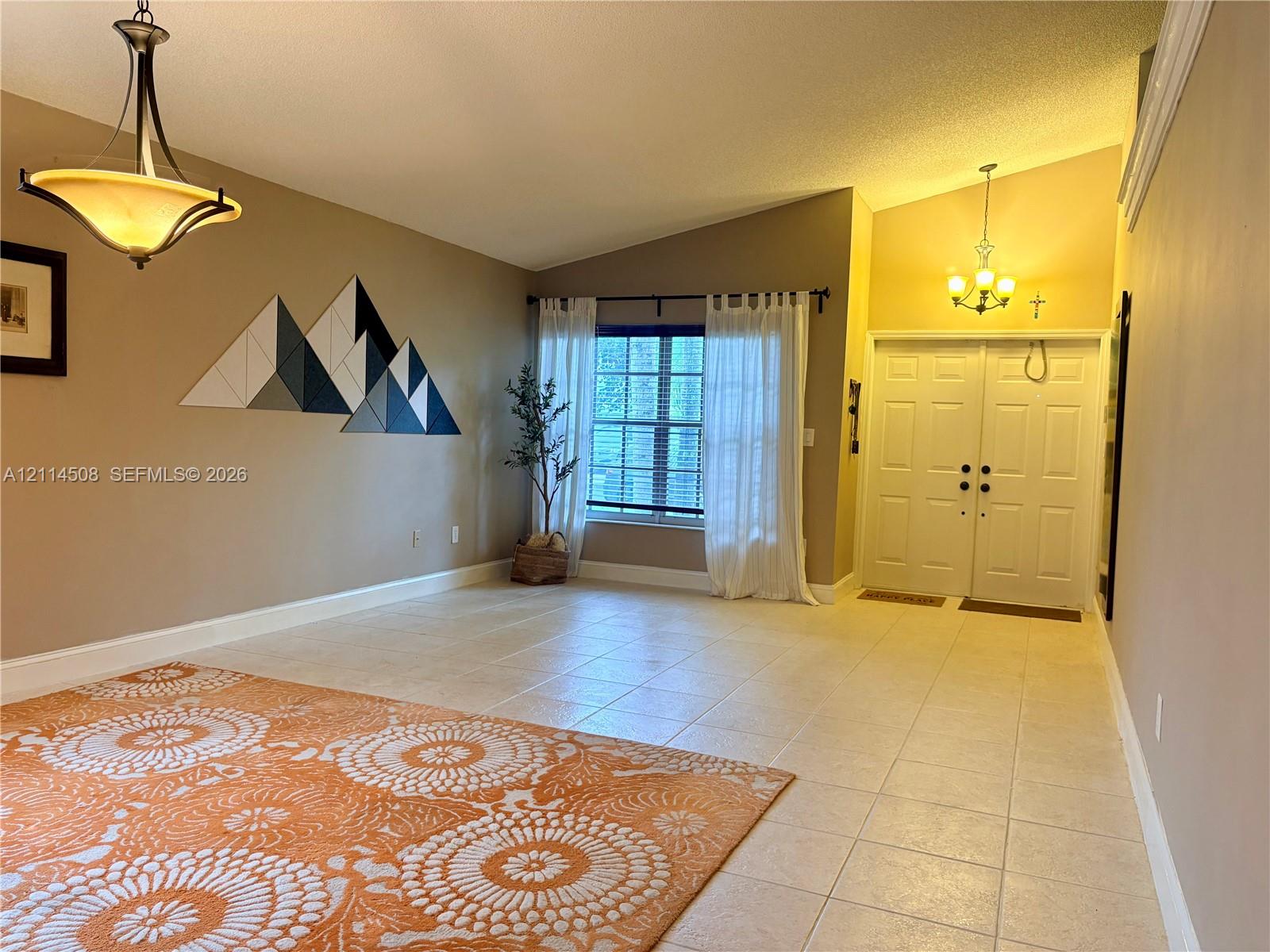 Vaulted ceilings, large-format tile flooring, double-entry front doors, and dual decorative chandeliers Vaulted ceilings, large-format tile flooring, double-entry front doors, and dual decorative chandeliers