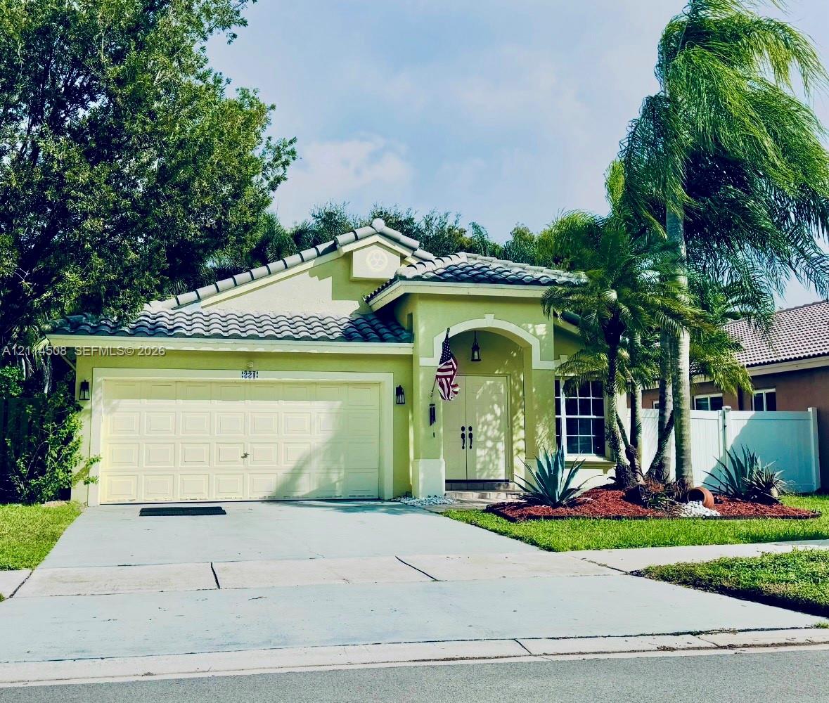 Stucco exterior featuring a tiled roof, arched entryway, double-door entrance, two-car garage, and established landscaping Stucco exterior featuring a tiled roof, arched entryway, double-door entrance, two-car garage, and established landscaping