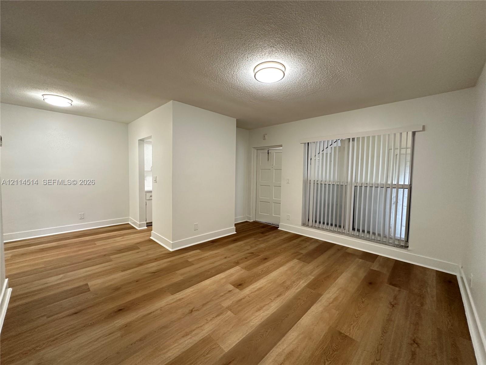 Wood-finish flooring, neutral walls, flush-mount ceiling lighting, and vertical window blinds Wood-finish flooring, neutral walls, flush-mount ceiling lighting, and vertical window blinds