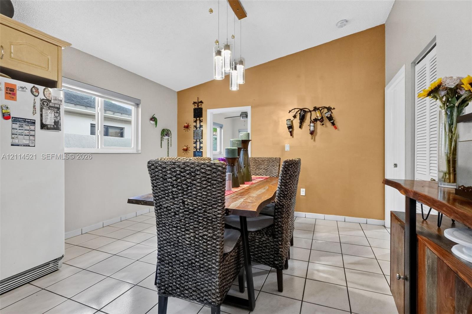 Vaulted ceiling, multi-pendant light fixture, tile flooring, and a single-hung window