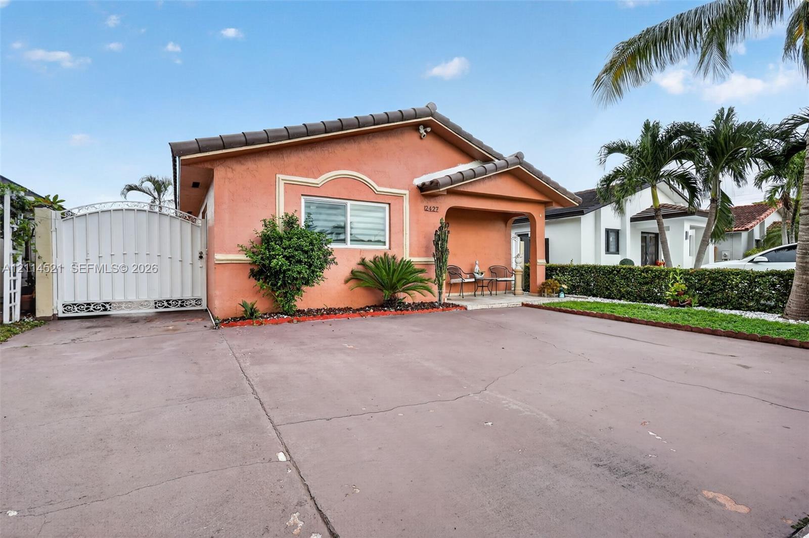 Stucco exterior featuring a covered entryway, tile roof, concrete driveway, and gated side access Stucco exterior featuring a covered entryway, tile roof, concrete driveway, and gated side access