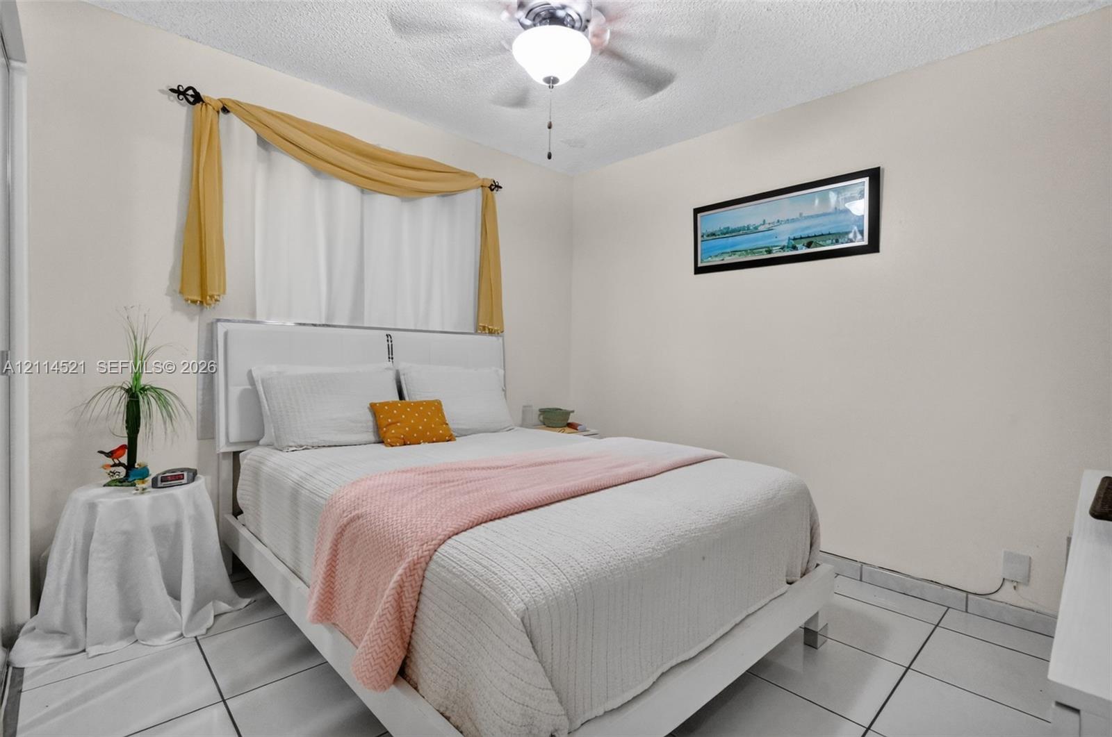 Interior space featuring white tiled flooring, textured ceiling, and a central ceiling fan with integrated lighting