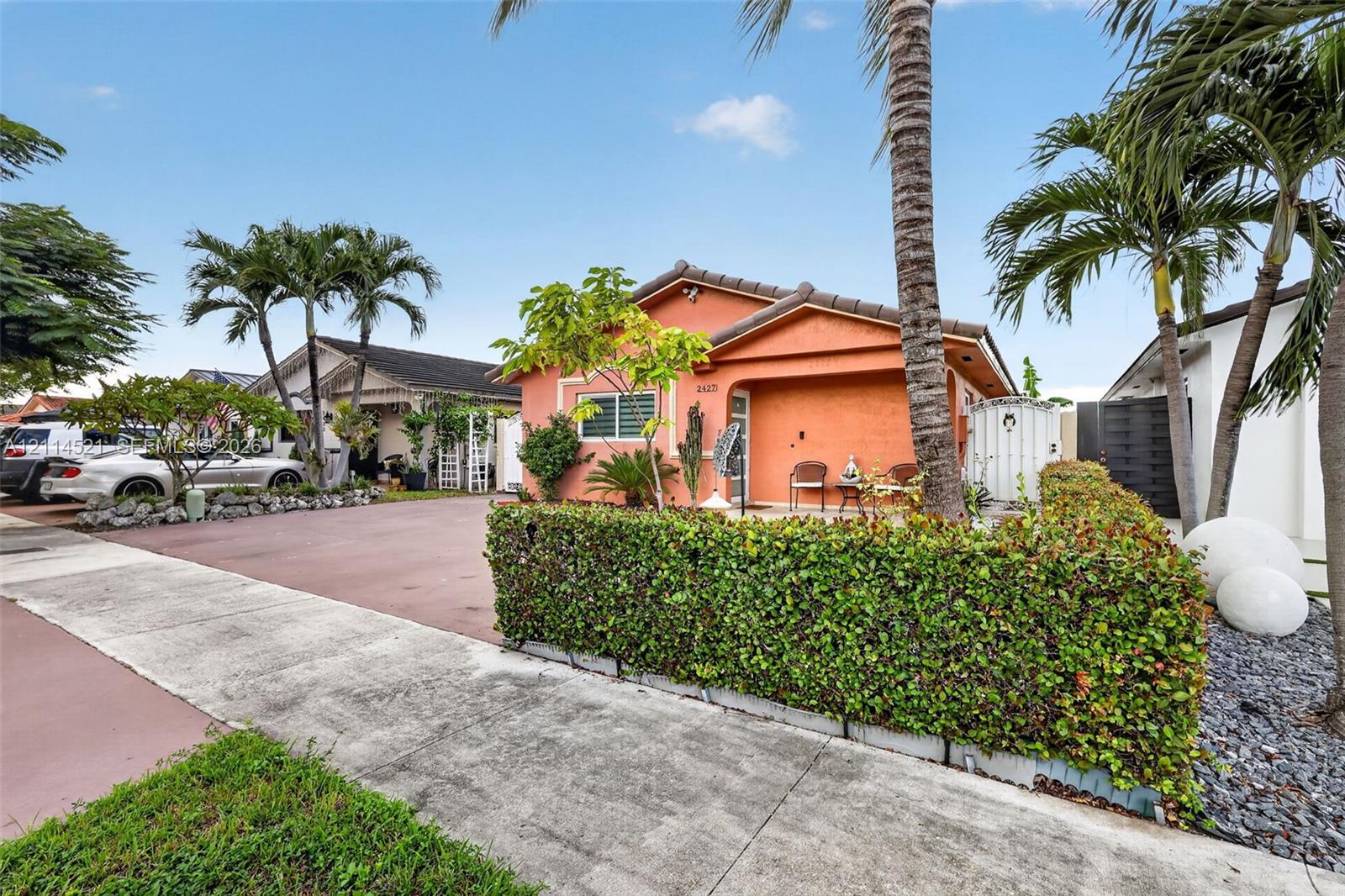 Stucco exterior residence featuring a covered front porch, paved driveway, and manicured hedge landscaping Stucco exterior residence featuring a covered front porch, paved driveway, and manicured hedge landscaping