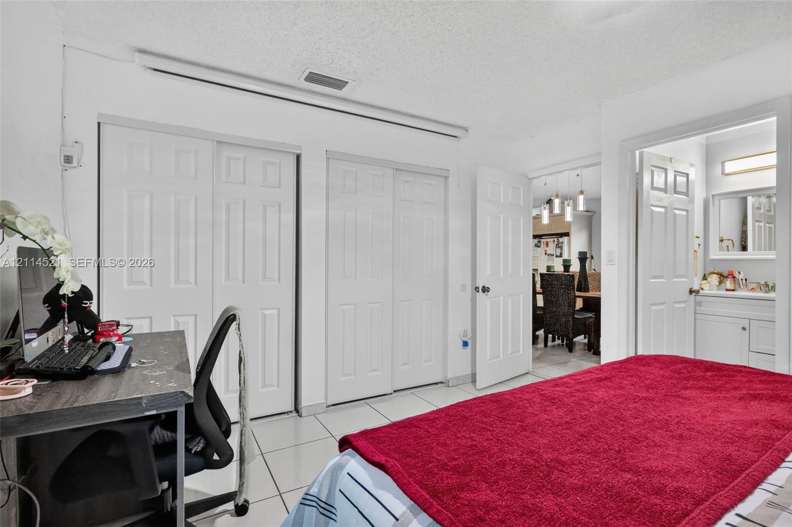 Room featuring large-format tile flooring, dual sets of white paneled sliding closet doors, and solid-core interior doors