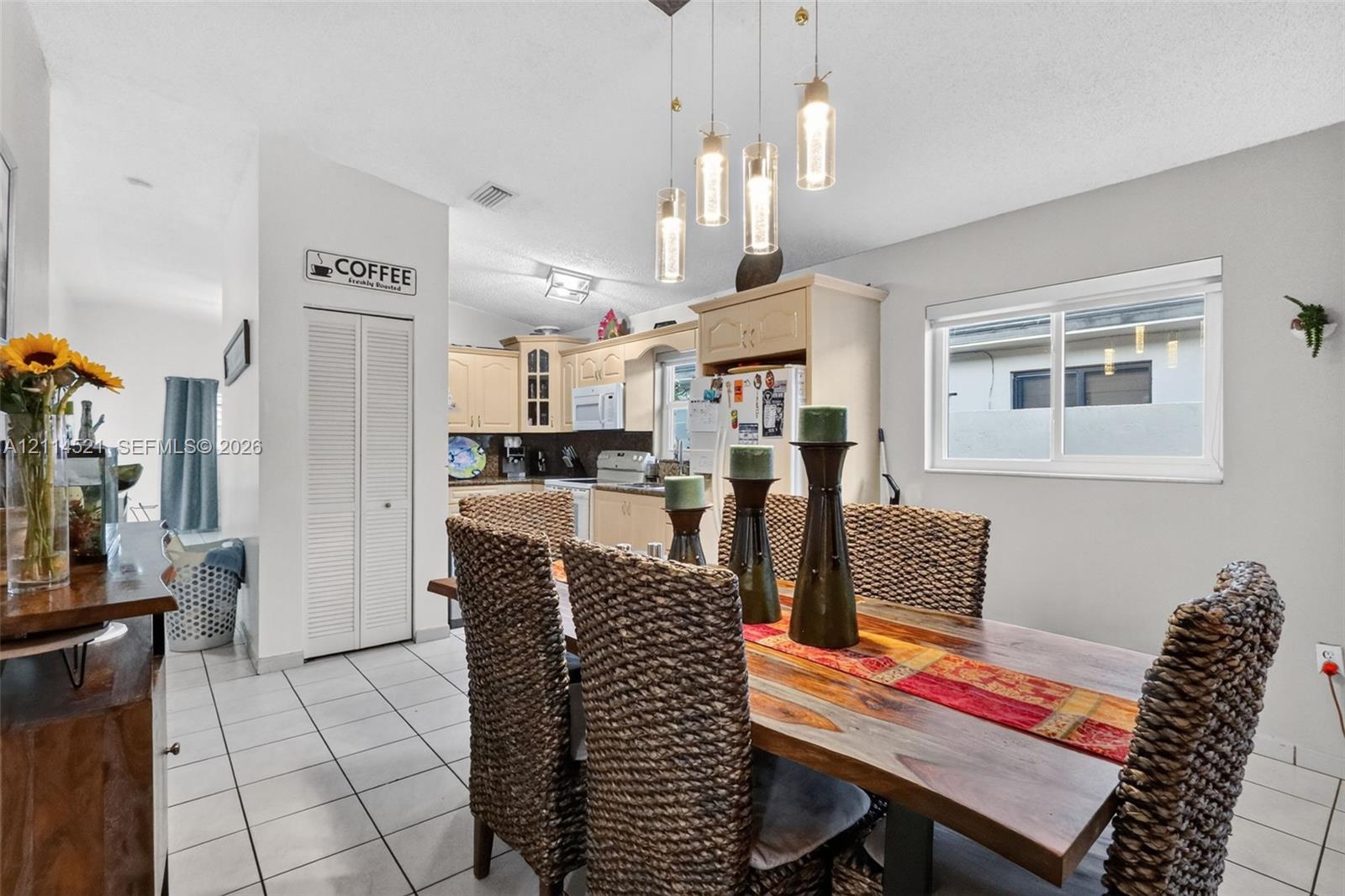 Dining area featuring ceramic tile flooring, a multi-light cylindrical glass pendant fixture, and white louvered closet doors