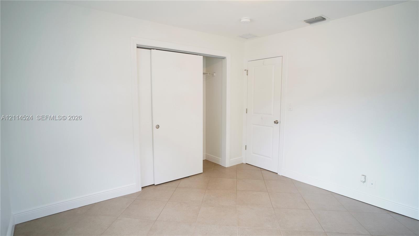 Neutral-toned ceramic tile flooring, sliding closet doors, and a solid-core paneled interior door