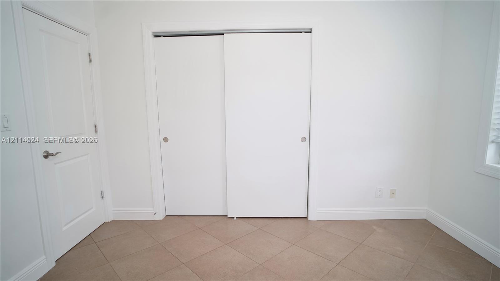Interior space featuring ceramic tile flooring, a two-panel sliding closet, and a classic-style swinging door